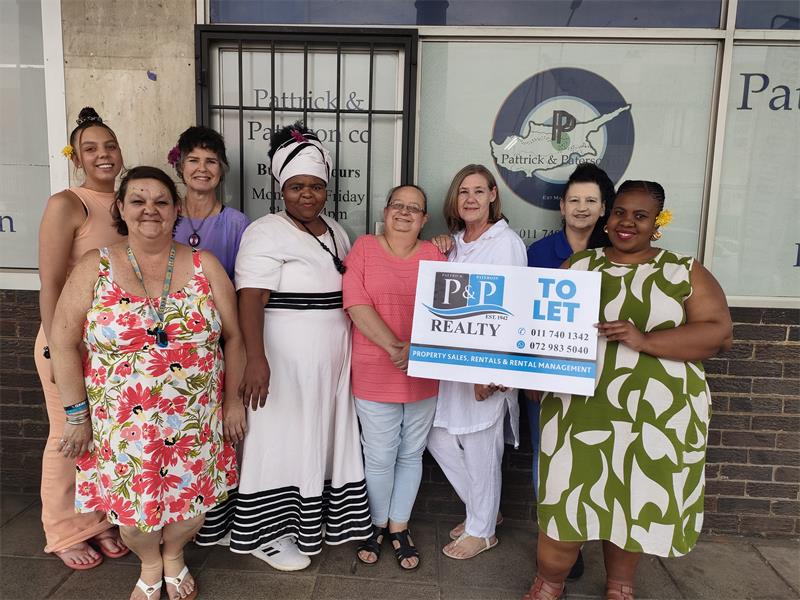 Joyful real estate agents and community members holding a 