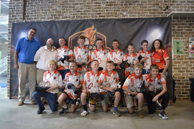 A group of cricket players in casual pants and red, orange and yellow shirts.