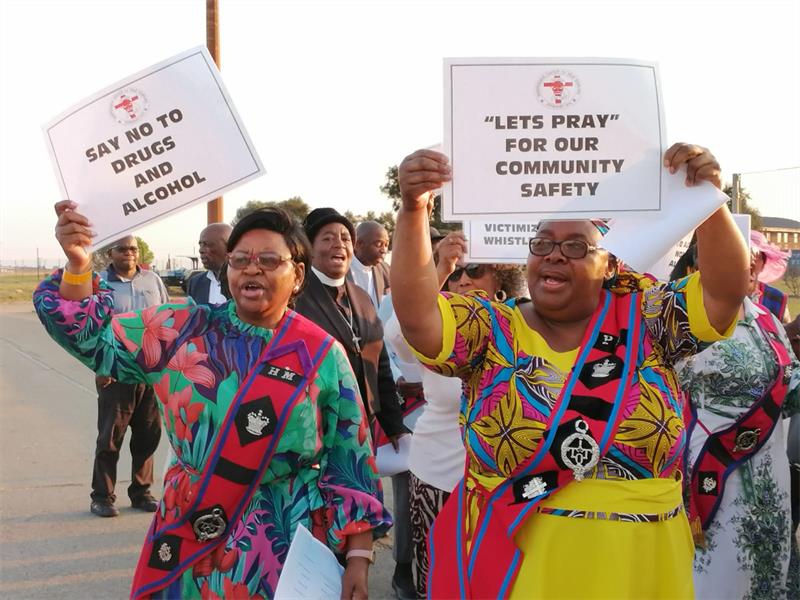 Church members gather with candles and placards at N17 toll plaza to seek divine protection and combat moral decay.