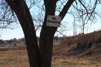 A no dumping sign is ignored by the metro as they still dumped a tree stump there.