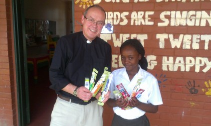 Reverend Robert Cotton (left) hand over toothbrushes as part of a dental health project that Vinet Maepa (12) is leading in the settlement.
