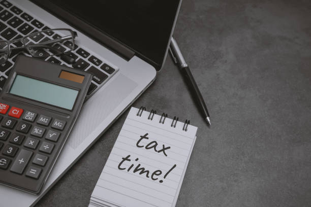 Tax Time written on notepad with laptop and calculator.
