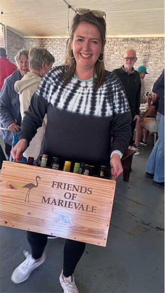 A woman holding a wooden box with bottles of wine.