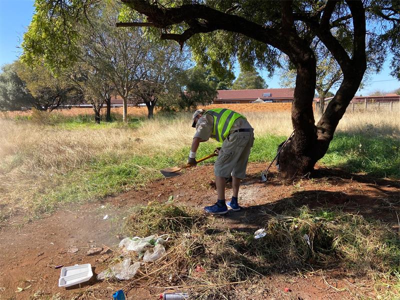 A man in a yellow vest is cleaning up trash.