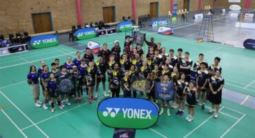 A group of people posing for a photo in a badminton court.