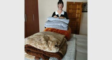 A woman standing next to a pile of blankets.