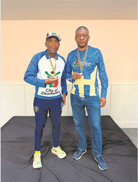 Two men standing next to each other holding medals.