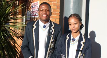 Two young people in school uniforms standing next to each other.
