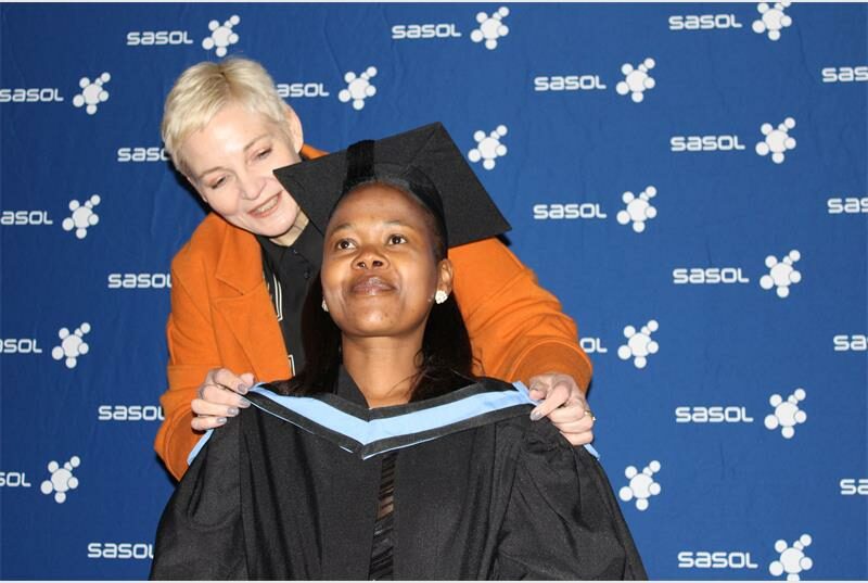 A woman in a graduation gown is holding up a woman in a graduation gown.