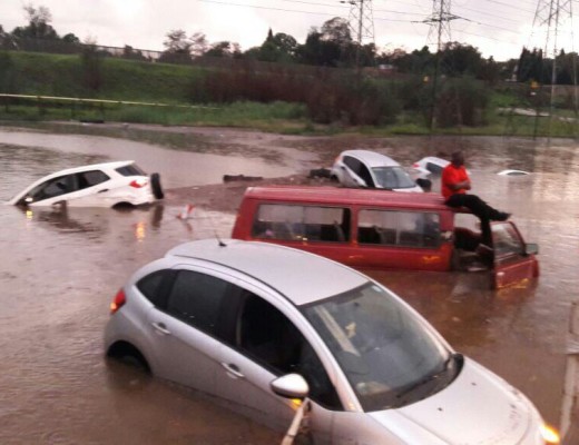 PEOPLE stand on the roof of a minibus taxi during the flooding.