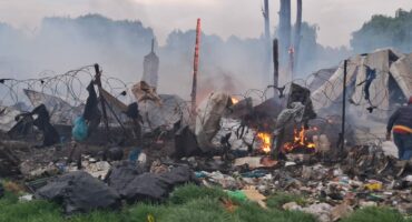 Charred debris and smoke at a fire scene after an incident involving destruction and damage.