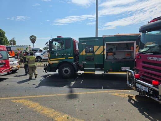 Emergency workers respond to a street accident with an ambulance and debris. Broken glass and colorful crates are scattered, conveying urgency and chaos.