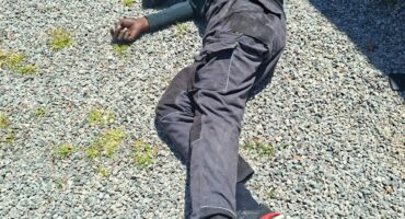 A suspect lies wounded on the ground in the bright sunlight.