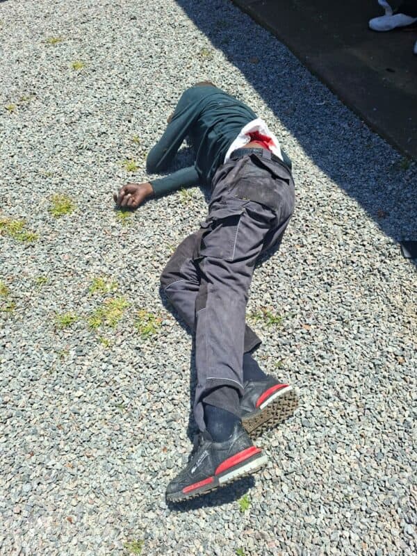 A suspect lies wounded on the ground in the bright sunlight.
