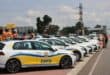 A line of white patrol cars with blue and yellow EMPD markings are parked on the roadside. Officers in orange vests stand nearby under a cloudy sky.