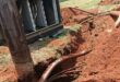 Underground cables exposed beside a utility box with open panels, surrounded by fresh red soil and dug trenches. The scene suggests ongoing repairs.