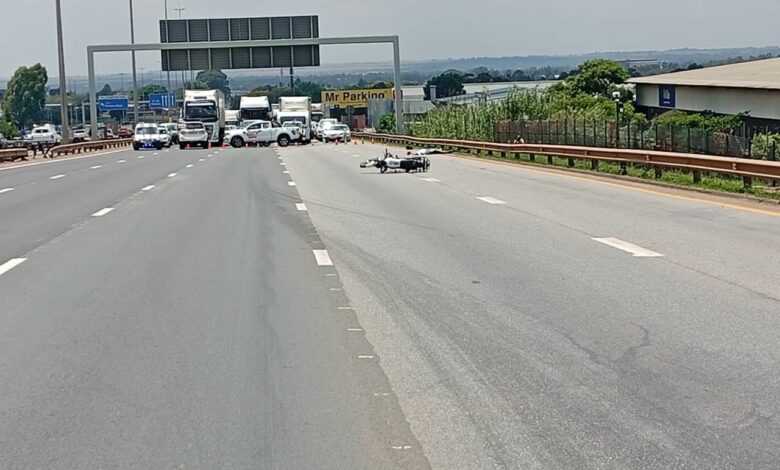 Wide highway with trucks and emergency vehicles blocking lanes ahead. A bike rests on the road surface. Overcast sky and a "Mr. Parking" sign visible.