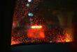 Raindrops on a car window with blurred red taillights in the background, creating a moody, nighttime atmosphere with a sense of calmness.