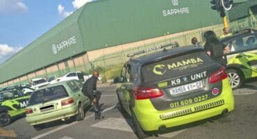 Security vehicles and personnel are gathered at an intersection near a large green building labeled "Sapphire." The scene appears tense and busy.