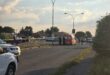Police officers and emergency vehicles at a blocked urban street during sunset, marked with caution tape. Sky is partly cloudy and atmosphere is serious.