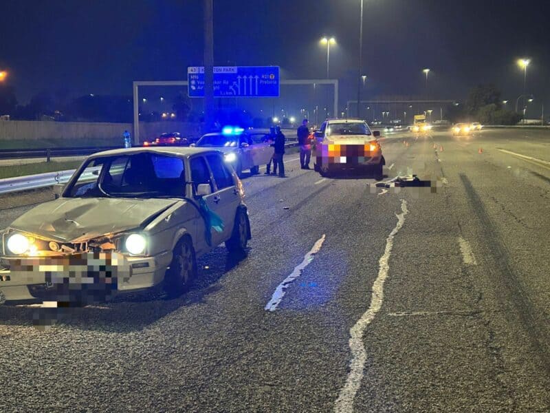 Damaged cars on a dimly lit highway at night, with police vehicles flashing blue lights. Officers and debris visible, conveying urgency and aftermath of a crash.