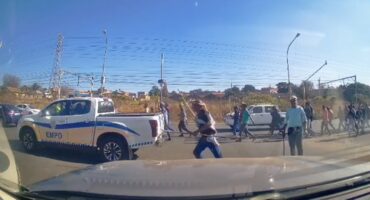 Group of people walking across street near parked EMPD police truck on a sunny day in a suburban area.