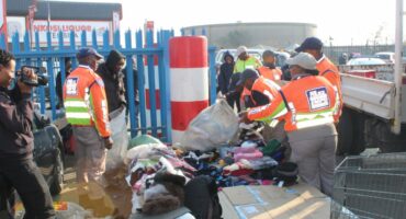 Law enforcement officers sorting through discarded clothing and items at a public area, promoting community cleanliness and safety.