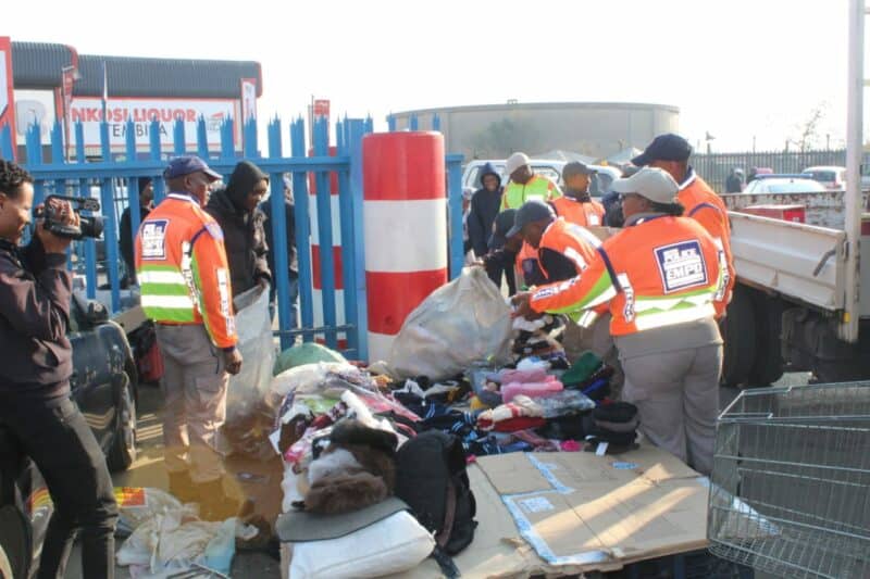Law enforcement officers sorting through discarded clothing and items at a public area, promoting community cleanliness and safety.