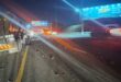 Nighttime highway scene with trucks, cars, streetlights, and billboards, featuring light streaks from vehicle headlights and lens flares.