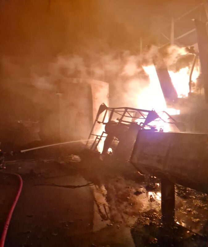 A fire scene with smoke and flames engulfing a structure, showcasing the aftermath of a significant blaze.