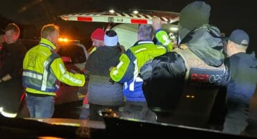 Emergency responders assisting individuals at night, with flashing lights illuminating the scene during a critical situation.
