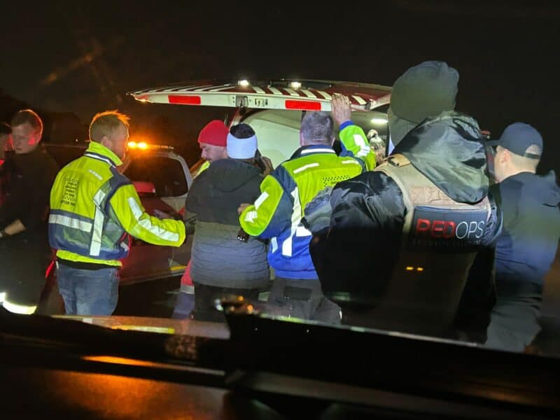 Emergency responders assisting individuals at night, with flashing lights illuminating the scene during a critical situation.