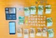 A collection of South African banknotes, coins, a digital scale, and small plastic bags arranged on a wooden surface.