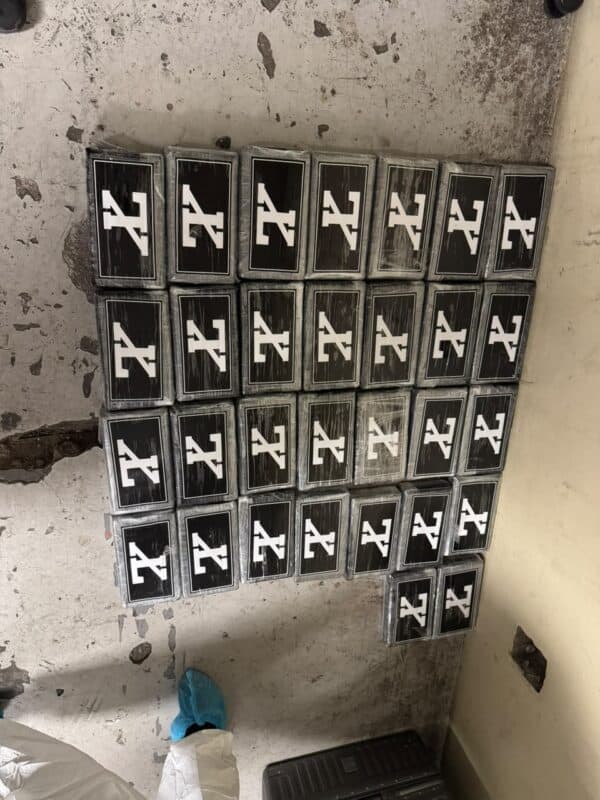 A grid of black-framed panels bearing white abstract symbols hangs on a worn concrete wall, creating a stark, industrial mood.