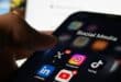 Close-up of a hand holding a smartphone showing social media apps, including Instagram, TikTok, LinkedIn, YouTube, Pinterest, and X.