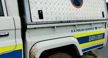 Close-up of a white-and-blue South African Police Service search and rescue truck, with a diamond-plate equipment compartment and muddy wheel arch.
