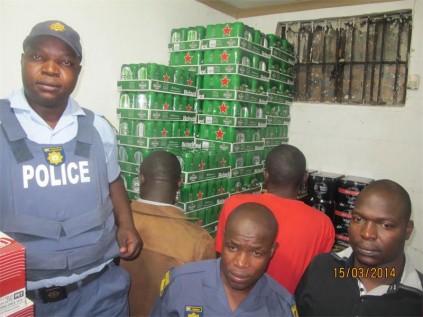 The two men who were arrested by the Germiston SAPS in a liquor bust, last Saturday, are watched by Consts Lindelani Mthembu (front, left), Dumisane Mdabula and Emanuel Maake.