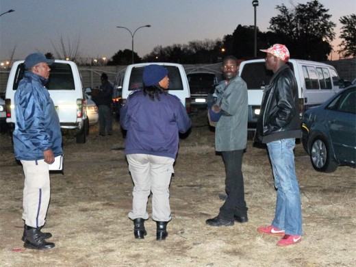 Metro police officers explain the procedure of reclaiming the impounded mini-bus taxis to drivers.