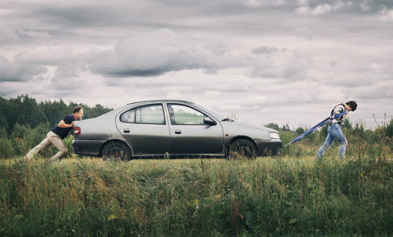 Couple pushing their broken car down the country road