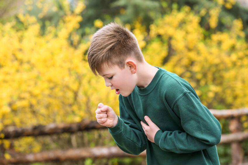 Boy having asthma attack outdoors on spring day