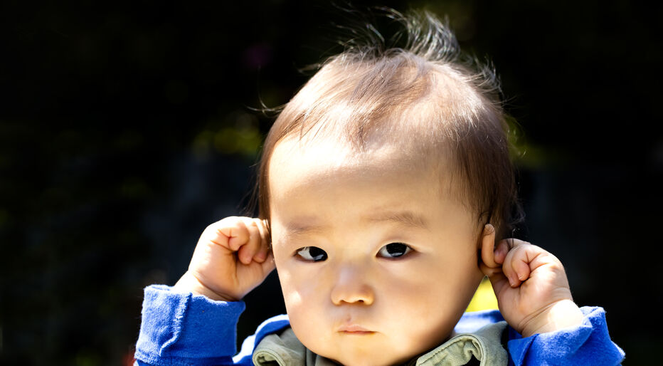 Baby touching his ears isolated on a black background and outdoors. Or hear no evil