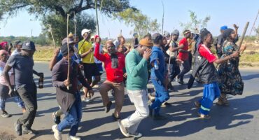 A group of demonstrators is currently moving along Pretoria Road towards Shamrock Road. The group proceeded down Rietfontein Road before turning onto Cactus Road and then right onto Pretoria Road. They are being monitored by a strong law enforcement presence, including SAPS and private security.