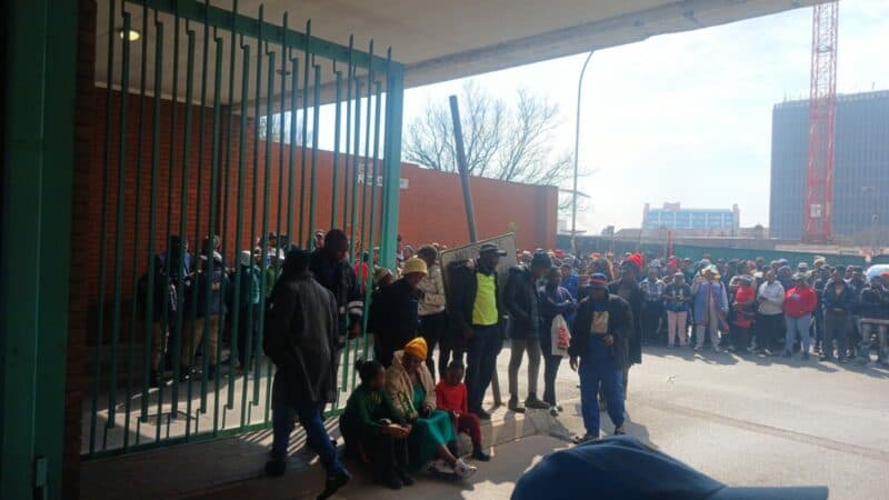 Dozens of protesters remain outside the Germiston Police Station, calling on the Department of Home Affairs to verify the immigration status of people detained during an operation in the Dukathole informal settlement.