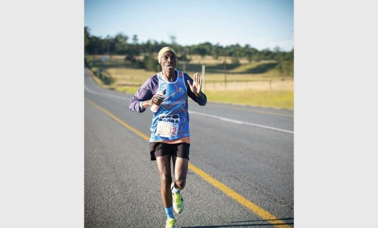 A man running in a marathon with his hands up.