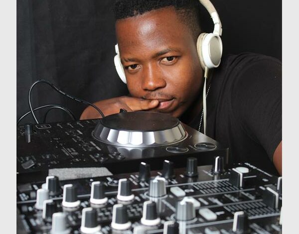 A man wearing headphones and standing next to a dj mixer.