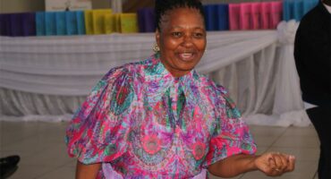 A woman in a colorful dress smiling at the camera.