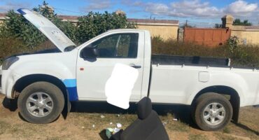 A white pick up truck with its hood open.