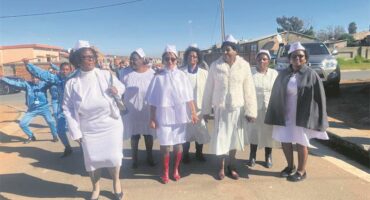 A group of women in white robes singing.