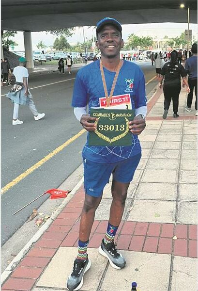 A man in blue shirt holding a medal.