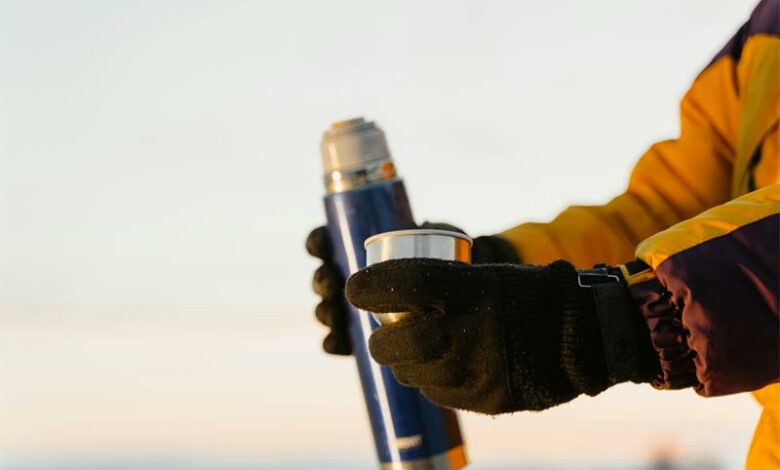 A person wearing gloves holding a blue and yellow bottle.